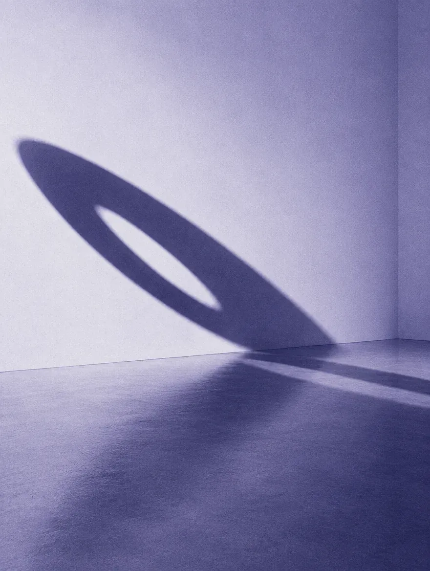 An elliptical shadow cast across a gallery floor