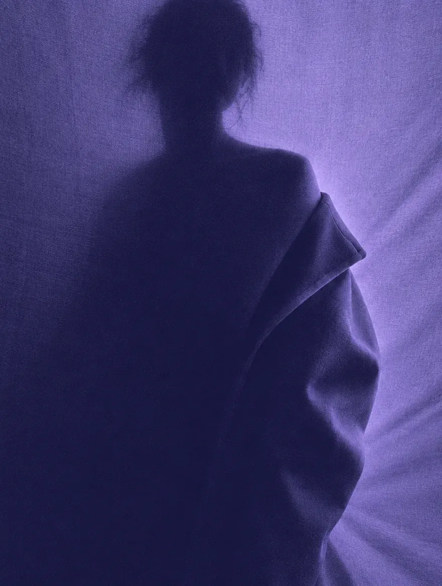 A silhouette in a long coat, sculpted by side light